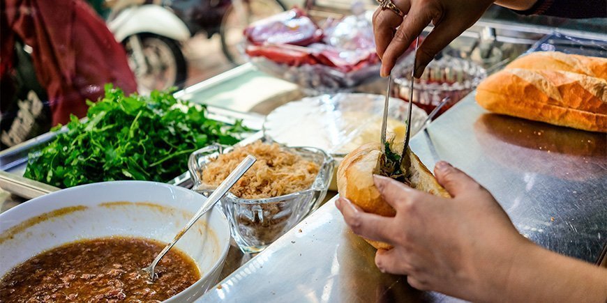Kvinde laver en Banh Mi-sanwich i Ho Chi Minh i Vietnam