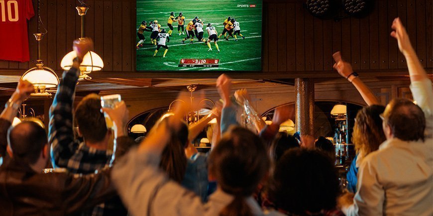 En gruppe mennesker ser amerikansk fodbold på en bar
