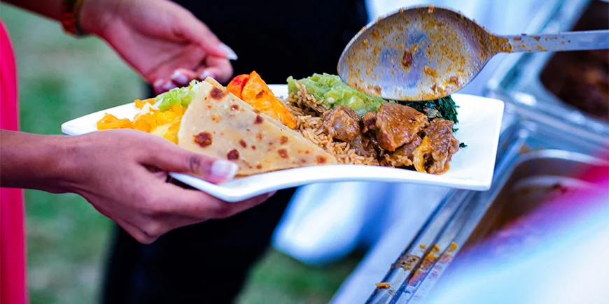 Kvinde holder en tallerken med mad i Kenya