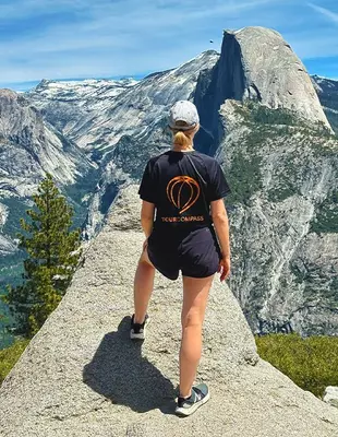 Kvinde i TourCompass-t-shirt på klippe i Yosemite